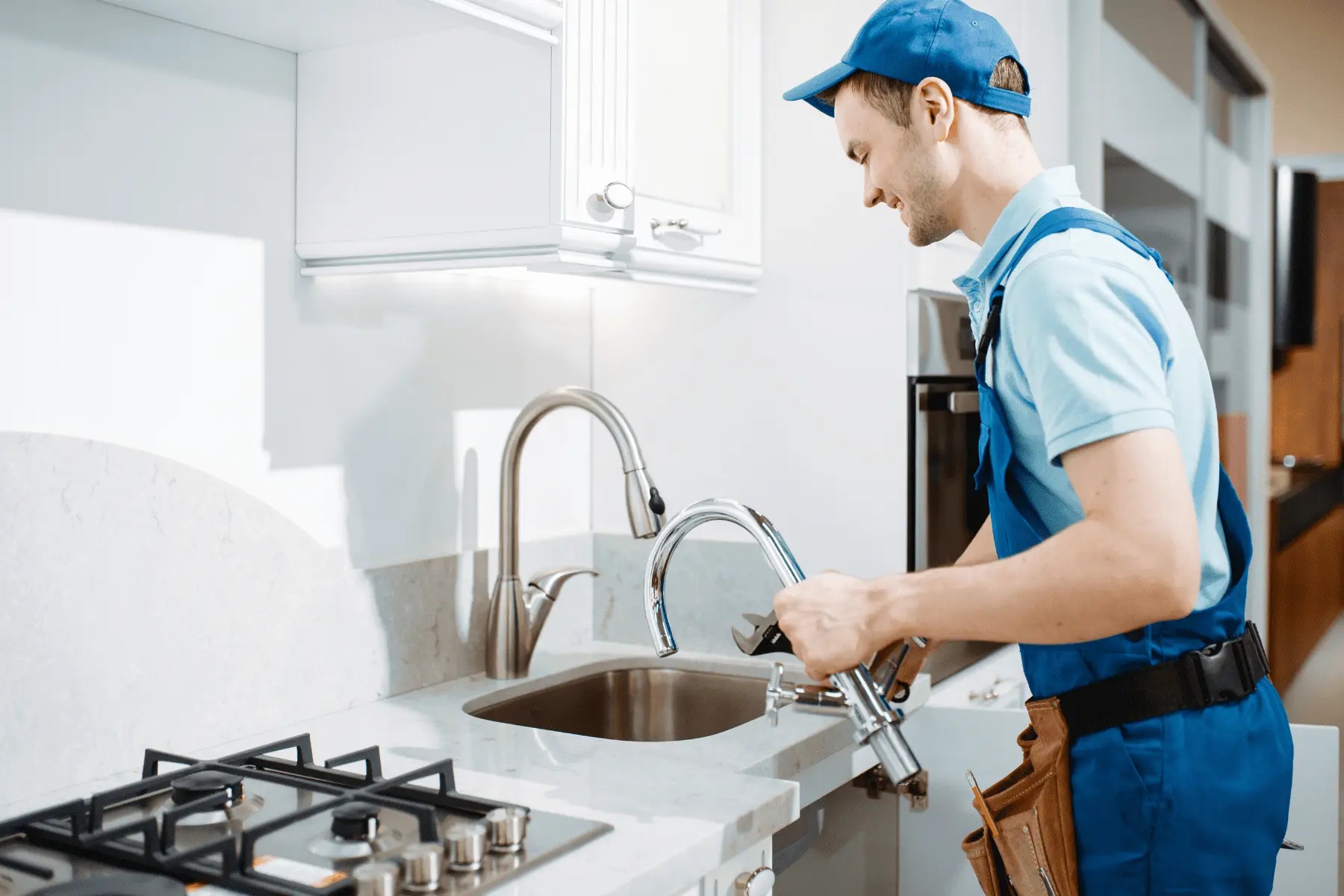 Idraulico al lavoro per un intervento rapido di riparazione di un lavandino in una cucina moderna a Roma.