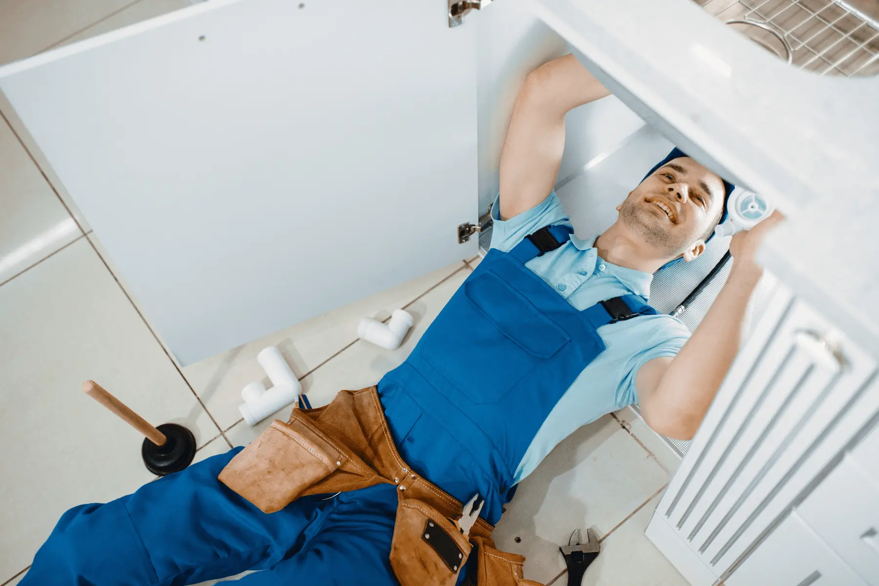 Idraulico che effettua una riparazione urgente sotto un lavandino per risolvere una perdita d'acqua in un bagno.