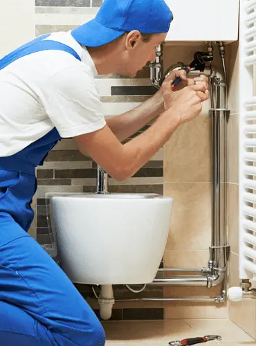 Un idraulico professionista di Edil Alba Restauri durante un intervento di riparazione e installazione dell'impianto idraulico di un WC in un bagno a Roma
