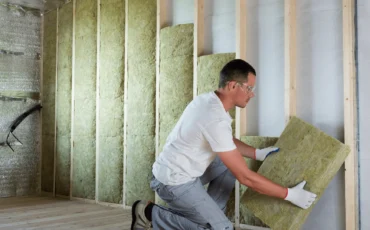 Tecnico che installa pannelli isolanti in una parete, a dimostrazione dei nostri interventi rapidi e flessibili per l'isolamento termico a Roma.