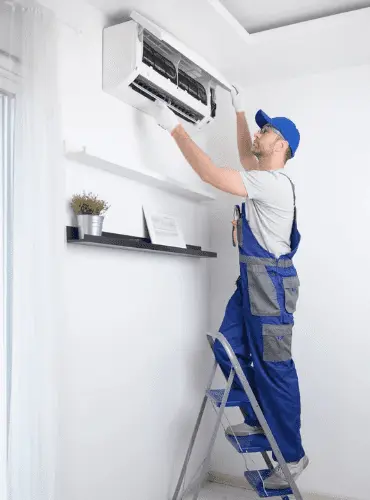 Un tecnico specializzato di Edil Alba Restauri su una scala che esegue la manutenzione e la pulizia dei filtri di un condizionatore a Roma.